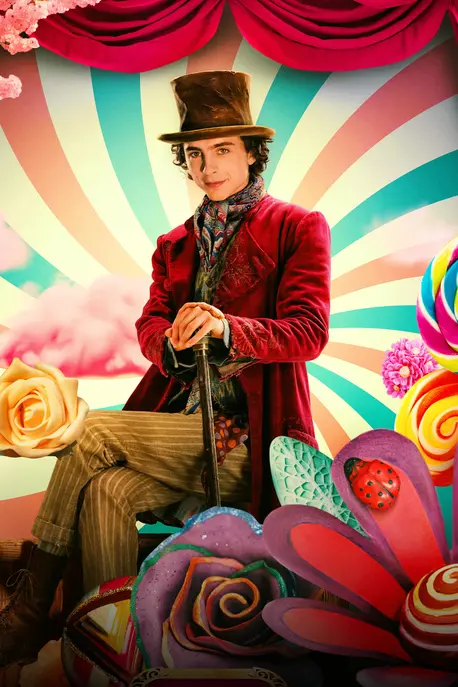 White man in a red suit and brown hat sits and holds a cane. The background is made of candy and bright colors